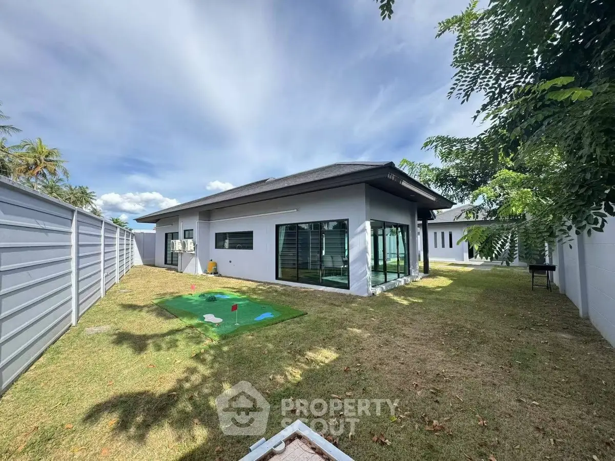 Modern single-story home with spacious backyard and putting green, perfect for outdoor activities and relaxation.