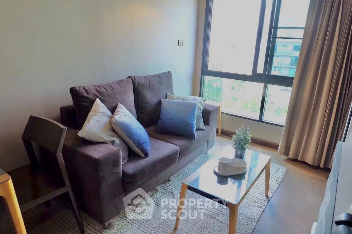 Modern living room with cozy sofa and large window offering natural light and city view.