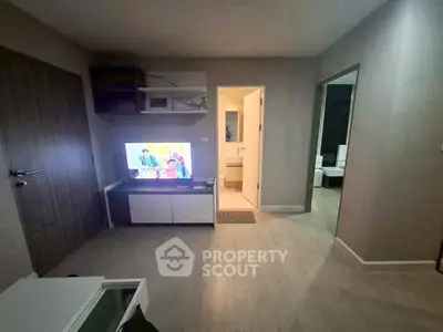 Cozy living room with modern decor and TV, leading to a bright bathroom and bedroom.