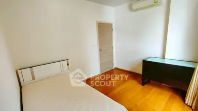 Cozy bedroom with wooden flooring and modern air conditioning unit.