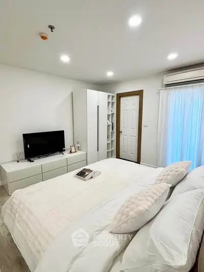 Modern bedroom with sleek design, featuring a cozy bed, TV, and ample storage in a bright, inviting space.