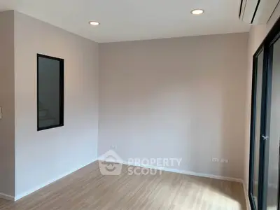Spacious empty room with wooden flooring and modern lighting, perfect for customization.