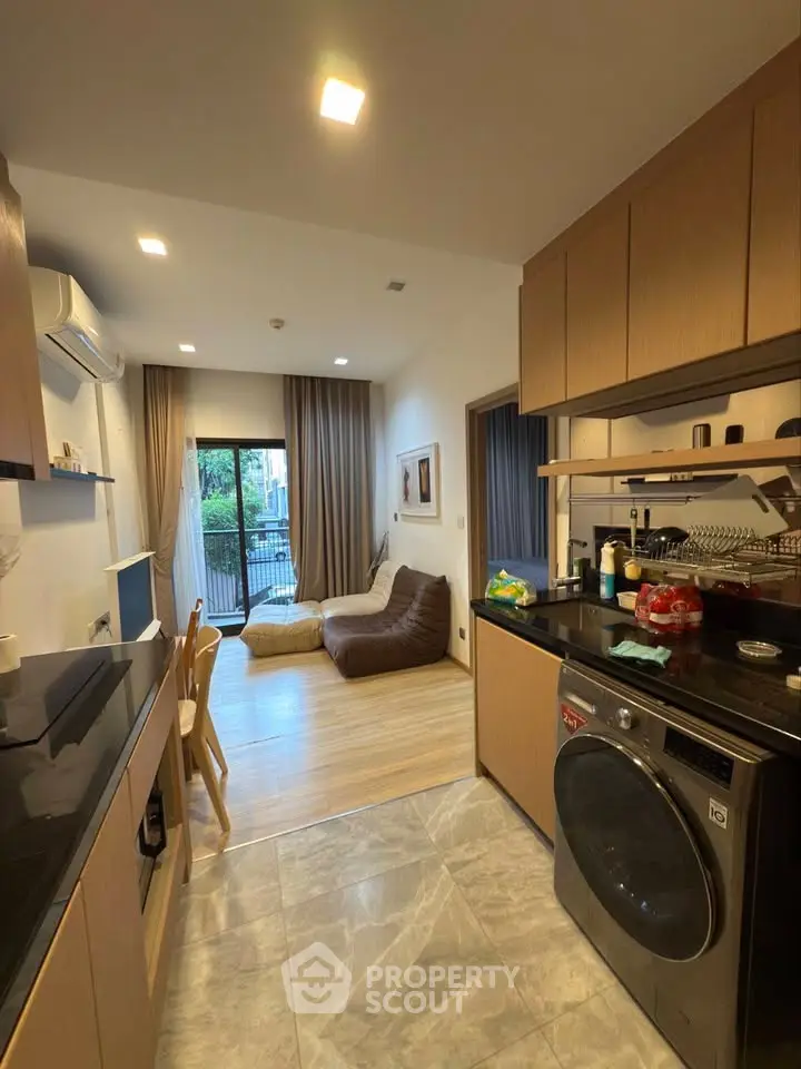 Modern open-layout kitchen and living room with balcony view in stylish apartment.