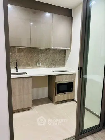 Modern compact kitchen with sleek cabinetry and built-in appliances in a stylish apartment.