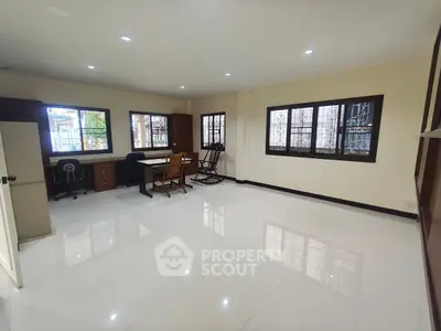 Spacious office room with modern furniture and large windows for natural light.