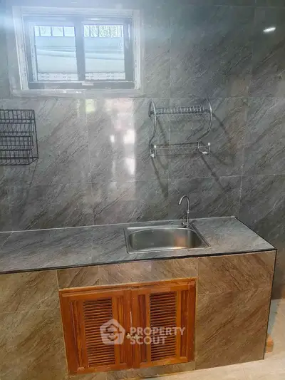 Modern kitchen with sleek countertop and stainless steel sink, featuring a minimalist design and ample storage space.