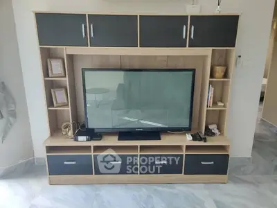 Modern living room with sleek TV unit and ample storage space.