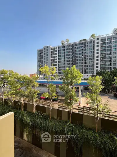 Modern apartment building with lush greenery and clear blue sky view.