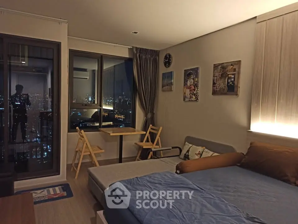 Cozy modern bedroom with city view, featuring stylish decor and a comfortable bed.
