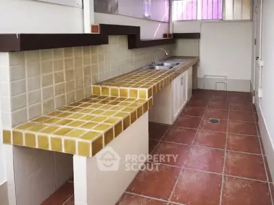 Spacious kitchen with tiled countertops and terracotta flooring, perfect for culinary enthusiasts.