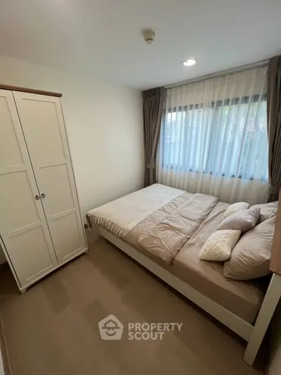 Cozy bedroom with natural light, featuring a comfortable bed and wardrobe, ideal for restful living.