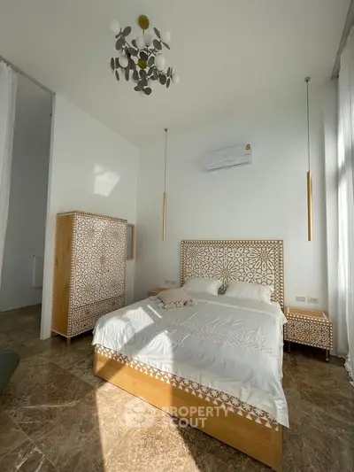 Luxurious bedroom with elegant decor and natural light, featuring a stylish bed and modern chandelier.