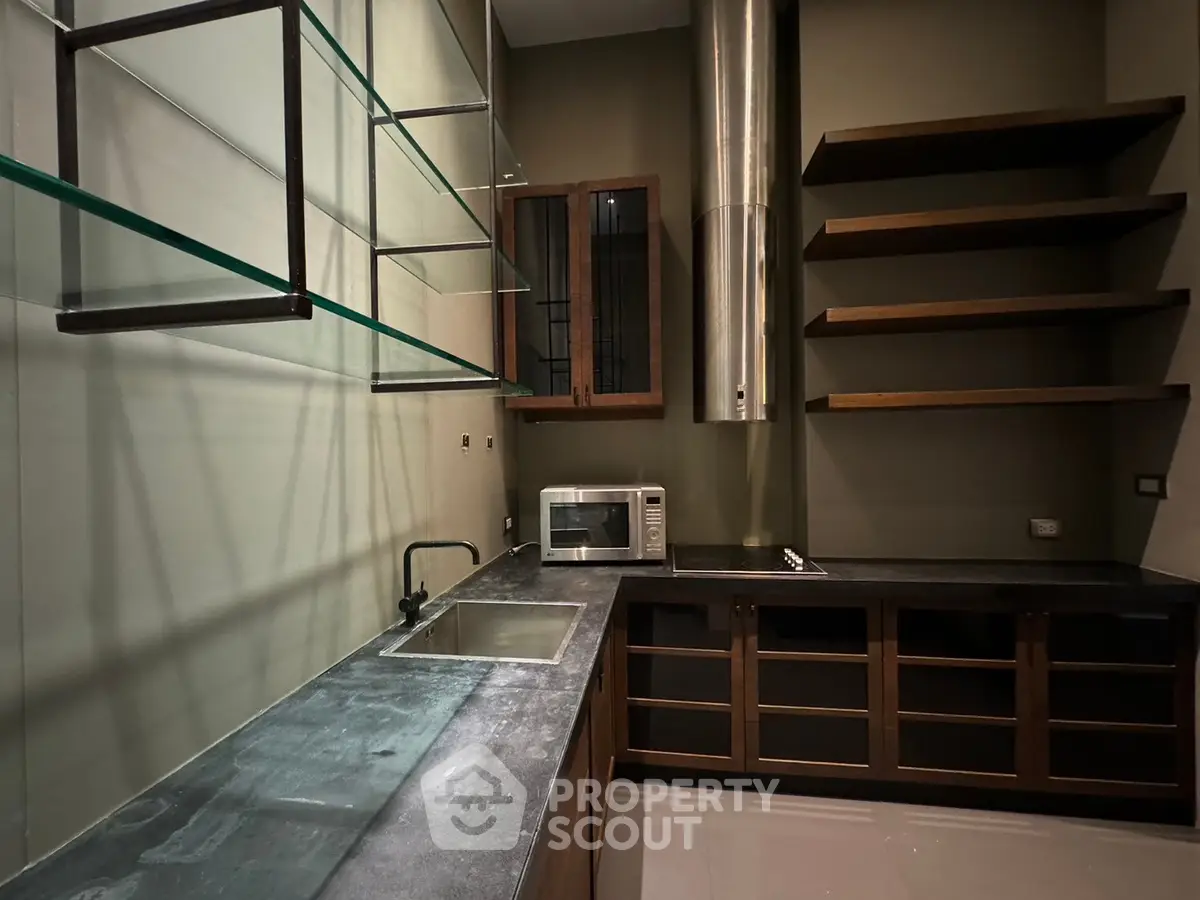 Modern kitchen with sleek countertops and open shelving, featuring a built-in microwave and stylish cabinetry.