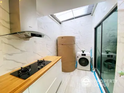 Modern kitchen with gas stove and laundry area in bright natural light