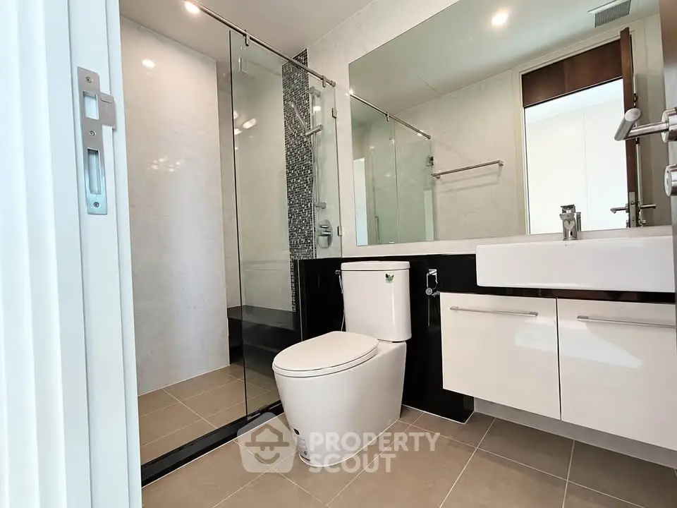 Modern bathroom with sleek fixtures and glass shower enclosure in a contemporary home.