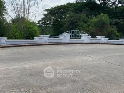 Spacious outdoor area with elegant white fence and lush greenery, perfect for relaxation and gatherings.