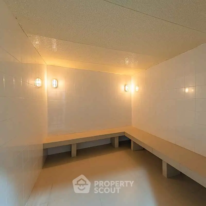 Spacious steam room with tiled walls and ambient lighting in modern building.