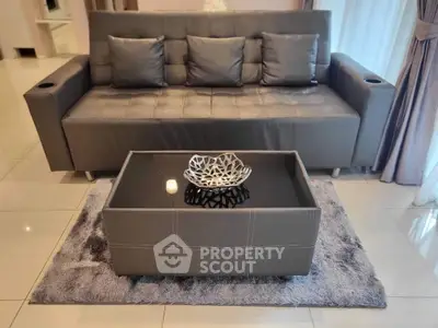 Modern living room with sleek gray sofa and stylish coffee table on plush rug.