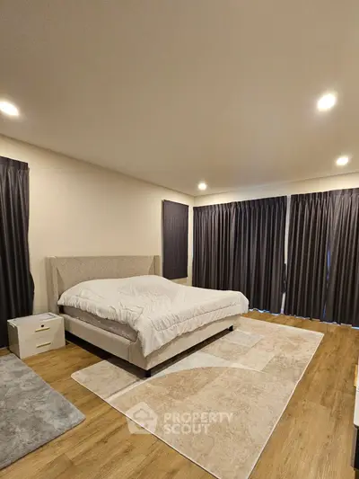 Spacious bedroom with modern decor and large windows for natural light.