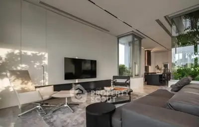 Luxurious modern living room with sleek furniture and large windows offering a serene garden view.