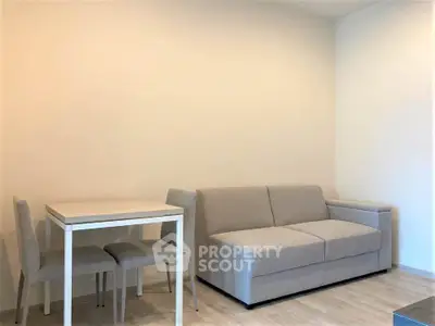 Modern minimalist living room with sleek gray sofa and compact dining set.