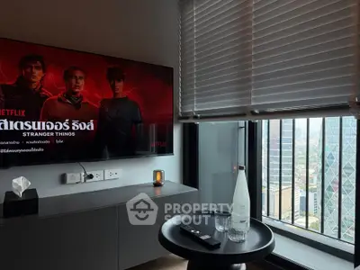 Modern living room with city view, featuring sleek furniture and large TV screen.