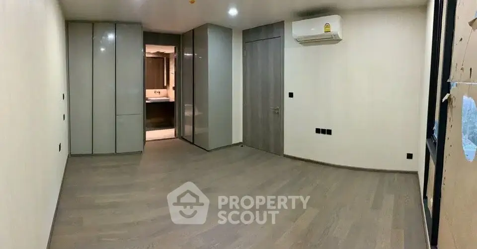 Spacious modern bedroom with sleek built-in wardrobes and air conditioning.