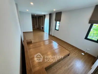 Spacious bedroom with wooden flooring and built-in closet, featuring large windows for natural light.