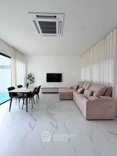 Modern living room with sleek furniture and pool view, featuring a spacious layout and elegant decor.