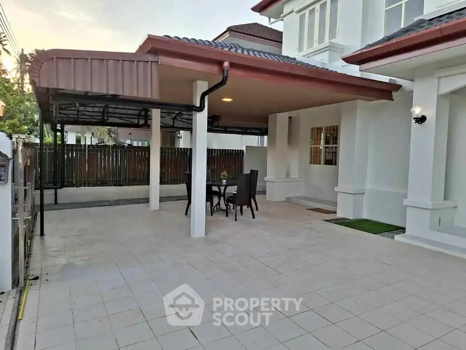 Spacious covered patio area in modern home with outdoor seating and tiled flooring.