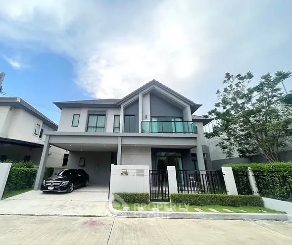 Modern two-story house with sleek design and spacious driveway in suburban neighborhood.