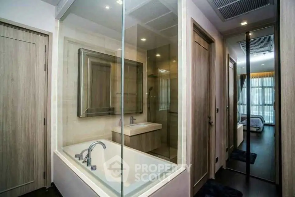 Modern bathroom with glass-enclosed bathtub and sleek design in luxury apartment.