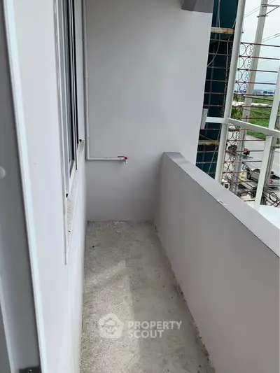 Compact balcony with concrete flooring and partial city view