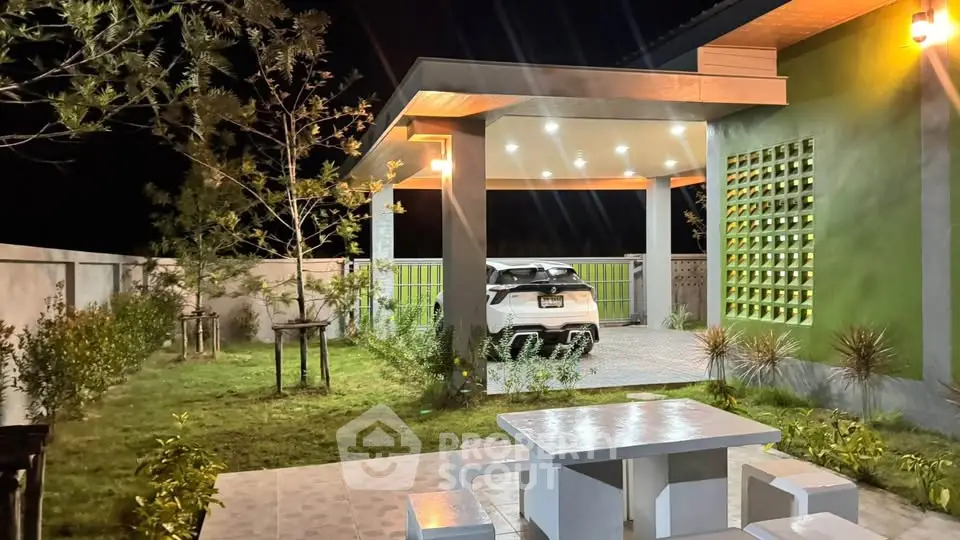 Modern home exterior with carport and garden at night, featuring sleek design and ambient lighting.
