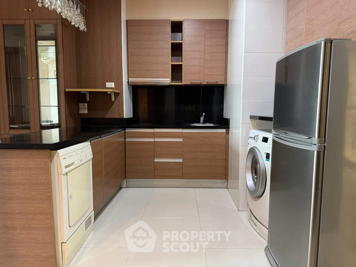 Modern kitchen with sleek wooden cabinets, dishwasher, and washing machine.