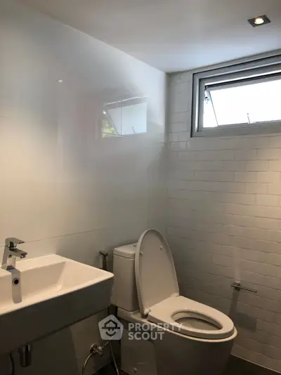Modern bathroom with sleek white tiles and compact fixtures.