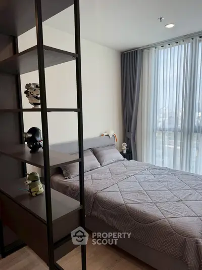 Modern bedroom with stylish decor and large window offering natural light