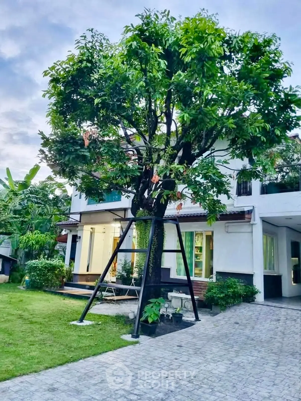 Charming two-story house with lush garden and mature tree in front yard