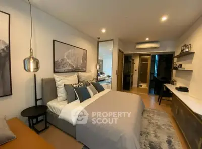 Elegantly furnished bedroom with a plush king-sized bed, modern lighting, and a seamless transition to an en-suite bathroom, showcasing a sophisticated urban living space.