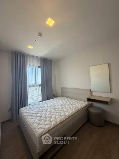 Modern bedroom with large window and minimalist decor in a high-rise apartment.