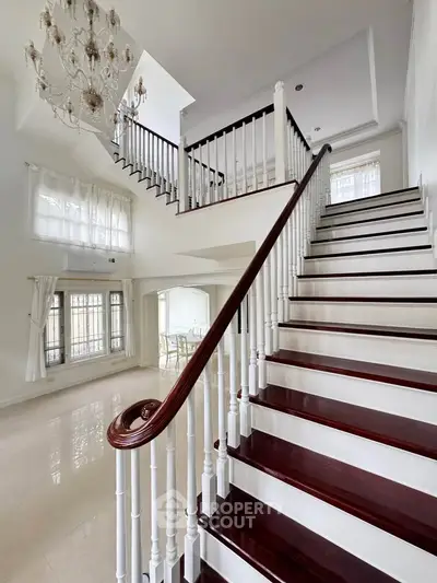 Elegant staircase in a spacious living area with chandelier and large windows