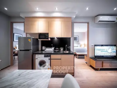 Modern open-plan kitchen with sleek appliances and cozy living area in stylish apartment.