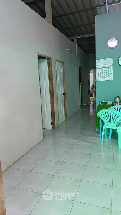 Simple interior hallway with tiled floor and plastic chairs, showcasing a modest living space.