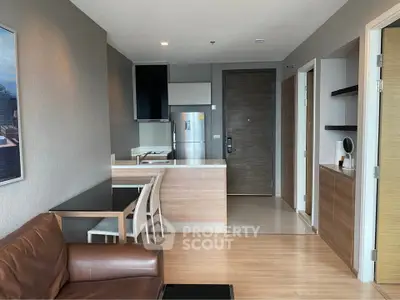 Modern open-layout living room with kitchen and dining area, featuring sleek furniture and wooden flooring.