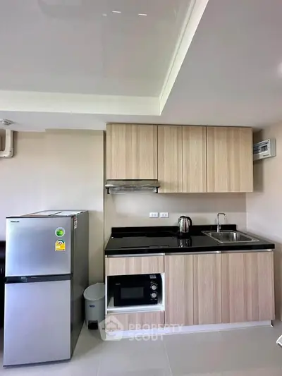 Modern kitchen with sleek cabinets, stainless steel fridge, and built-in microwave in a stylish apartment.