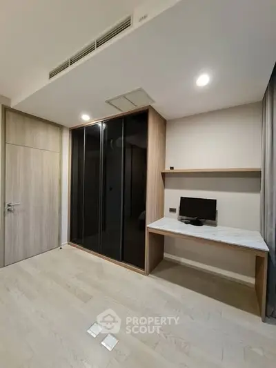 Modern study room with built-in desk and sleek wardrobe in a minimalist apartment.