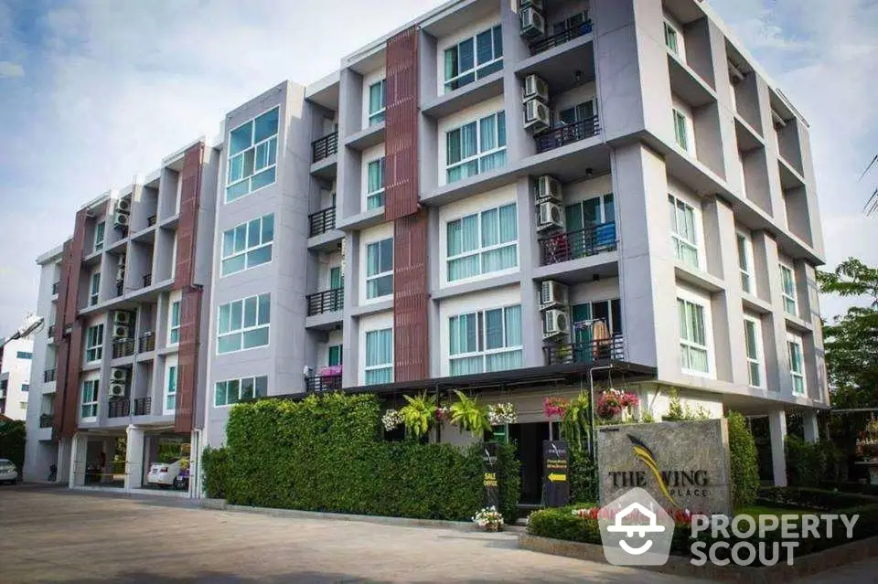 Modern apartment building with lush greenery and spacious balconies in urban setting.