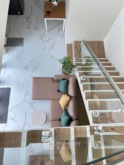Modern loft interior with stylish staircase and cozy seating area, featuring elegant marble flooring.