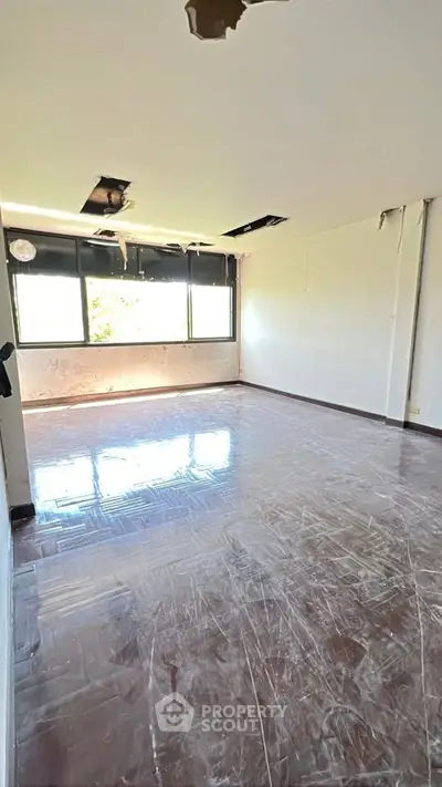 Spacious room with large window and natural light, ideal for renovation.