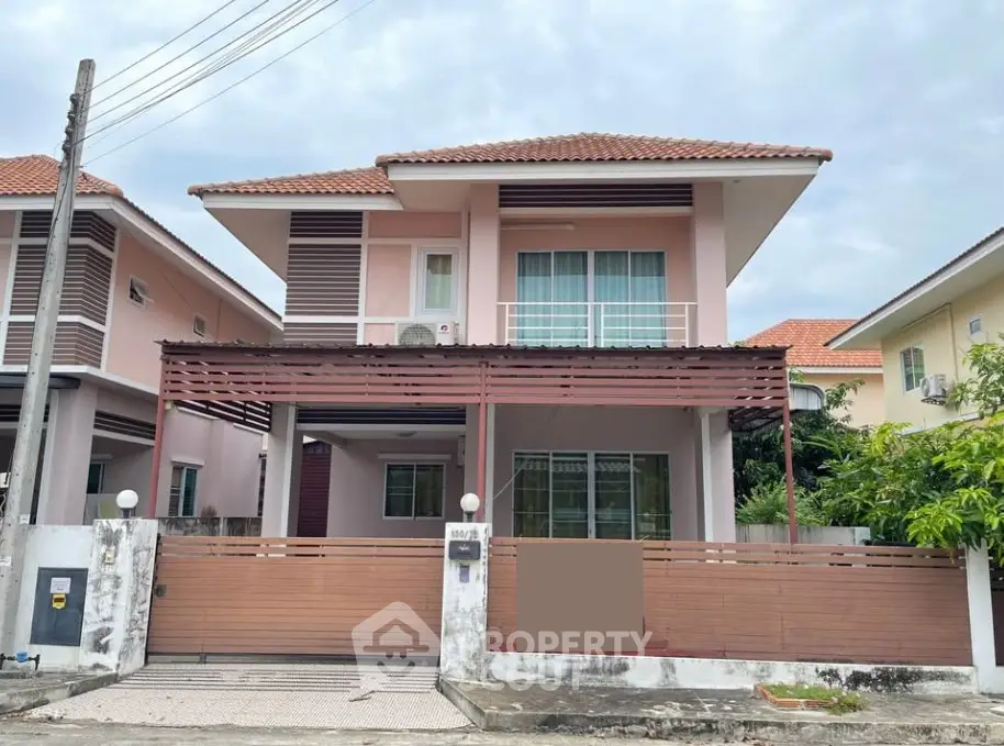 Charming two-story house with a tiled roof and gated entrance in a suburban neighborhood.